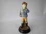 Antique Continental majolica Winter Boy ceramic figurine circa 1890–1910, wearing a blue coat and scarf and holding snowballs beside a stone wall.