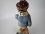 Antique Continental majolica Winter Boy ceramic figurine circa 1890–1910, wearing a blue coat and scarf and holding snowballs beside a stone wall.