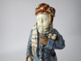 Antique Continental majolica Winter Boy ceramic figurine circa 1890–1910, wearing a blue coat and scarf and holding snowballs beside a stone wall.
