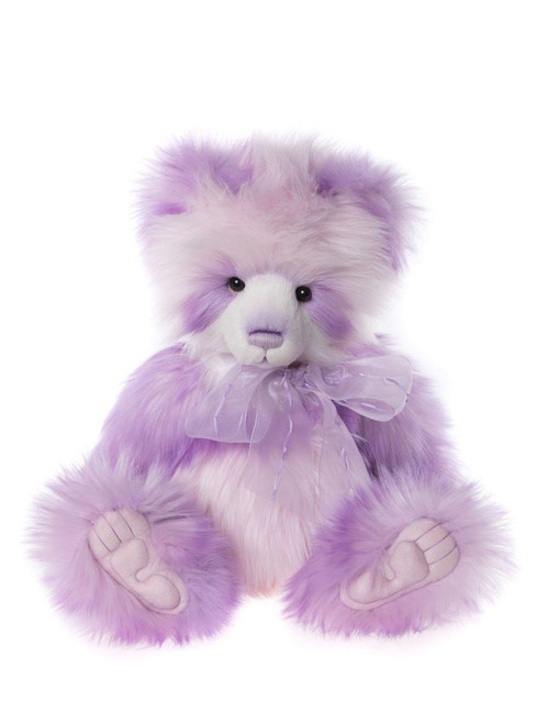 A purple and white fluffy teddy bear sits upright against a white background, wearing a sheer lavender ribbon bow tied at its neck.