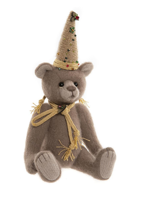 A brown plush teddy bear sits upright, wearing a jewel-decorated conical party hat and a braided gold rope necktie with fringe ends, against a white background.