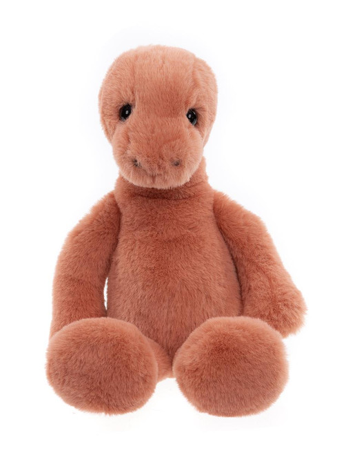 A terracotta/salmon-colored plush dinosaur teddy bear sits upright against a white background, featuring small white back spines, shiny black eyes, and an elongated neck.