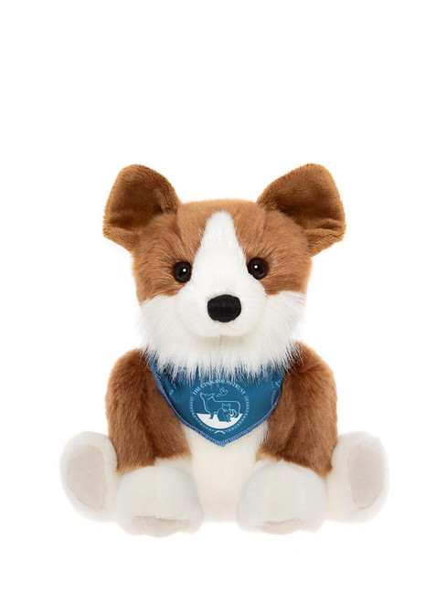 A Corgi plush toy sits upright against a white background, wearing a blue bandana reading "The Cinnamon Trust."