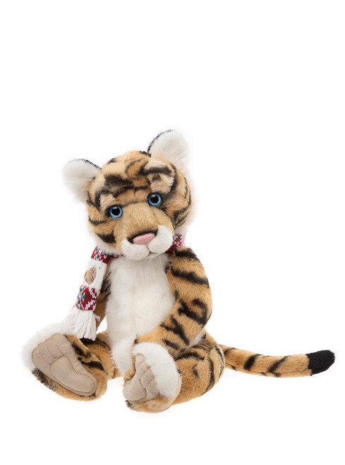 A tiger cub plush toy sits upright against a white background, wearing a red and white knitted scarf and small suede moccasin slippers, with bright blue eyes.