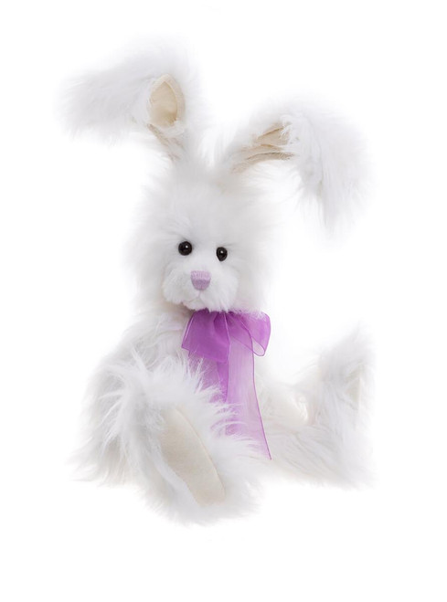 A white fluffy plush bunny rabbit sits upright against a white background, adorned with a sheer purple bow tied at its neck.