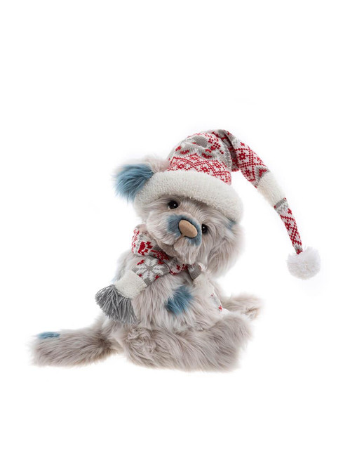 A grey and blue plush teddy bear sits posed wearing a red and white Nordic-patterned Santa hat with pompom and matching scarf, against a white background.