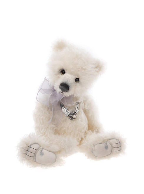 A white fluffy Charlie Bears teddy bear sits upright, wearing a sheer lavender ribbon bow and a decorative bead necklace, with grey paw pads, against a white background.