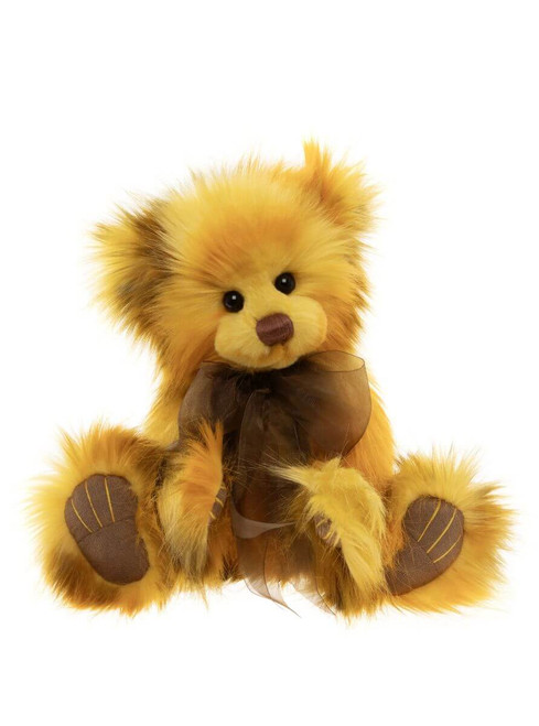 A golden yellow fluffy teddy bear sits upright against a white background, wearing a sheer dark brown ribbon bow tied around its neck. It has brown leather-look paw pads.