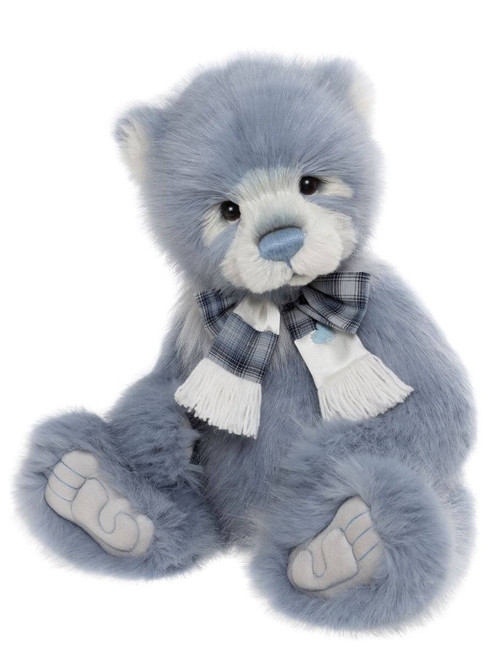 A blue-grey plush teddy bear sits upright, wearing a blue plaid bow-tied scarf with white fringed ends, featuring a light blue nose and embroidered paw pads.