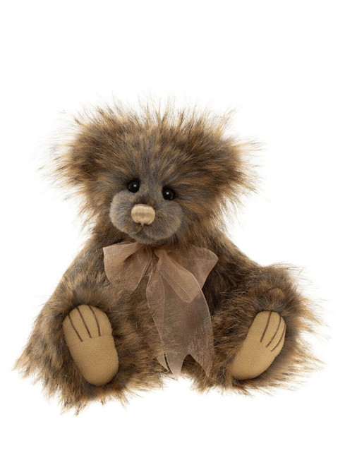A fluffy, shaggy brown teddy bear sits upright against a white background, wearing a sheer golden ribbon bow tie, with suede-style paws and small dark eyes.