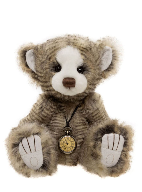 A striped grey-brown Charlie Bear teddy sits upright against a white background, wearing a vintage brass pocket watch on a cord necklace. It has white paw pads and a white muzzle.