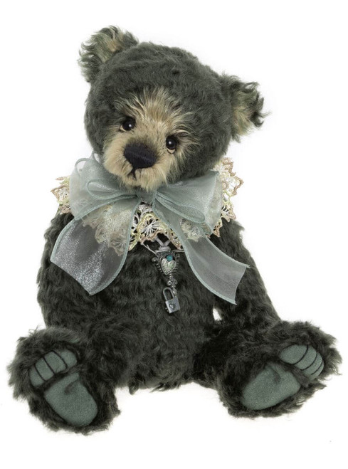 A dark grey mohair Charlie Bear sits upright, wearing a lace collar, sheer blue ribbon bow, and a decorative silver key and padlock charm pendant.