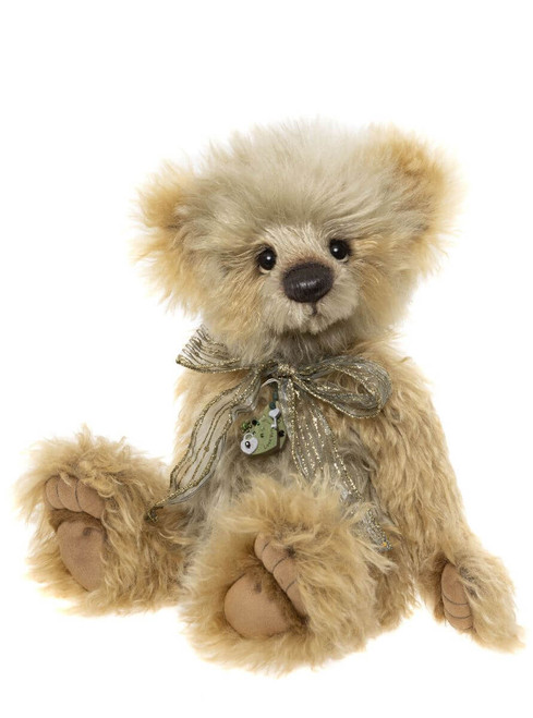 A fluffy golden-beige Charlie Bear teddy sits upright, wearing a shimmery gold ribbon bow with a small green heart-shaped padlock charm pendant, against a white background.