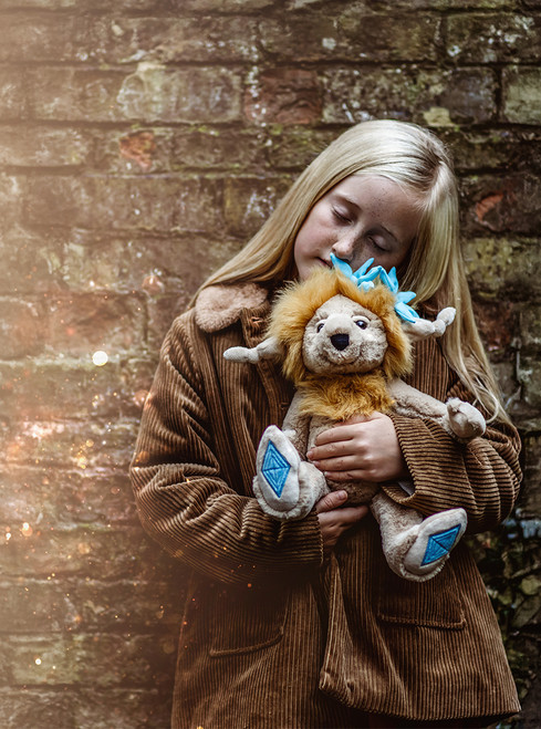A beige lion Charlie Bear plush toy sits upright, featuring a golden mane, blue spiky hair accents, and blue diamond embroidery on its oversized paws, against a white background.