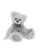 A white and grey fluffy Charlie Bear teddy sits upright, wearing a grey organza ribbon bow with a silver filigree heart charm pendant, against a white background.