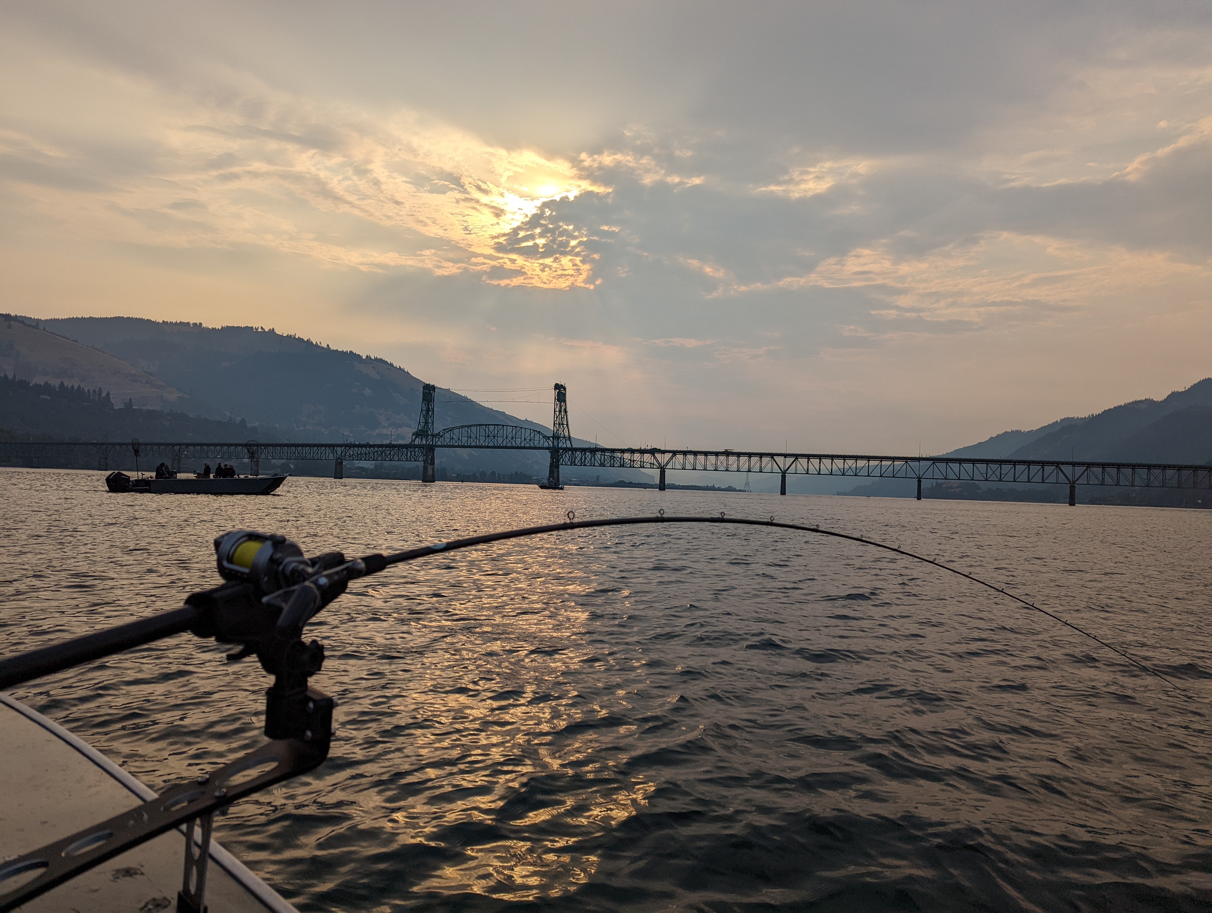 Fishing rod hooked to boat at sunrise