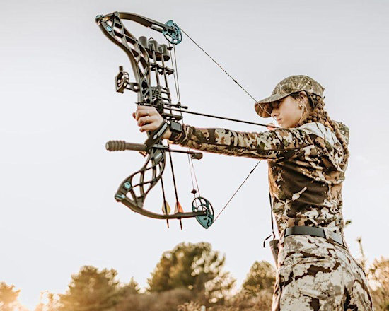 An archer wearing camouflage holds a compound bow at full draw, represenRng skilled archery and hunter safety.