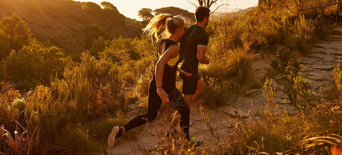 Two people running on a mountain trail