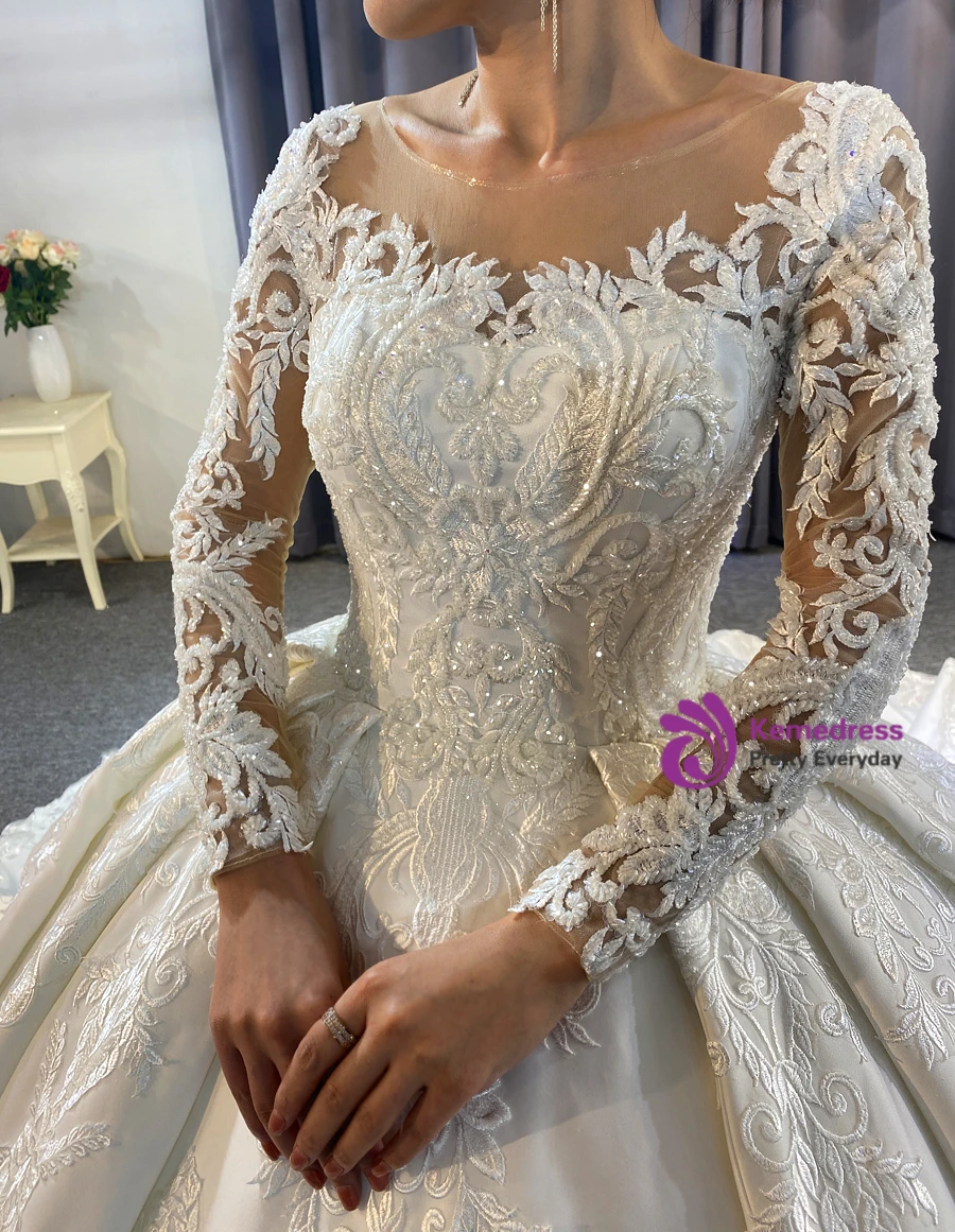 Close up of heavy satin fabric and raised floral appliqué details on a white ball gown wedding dress