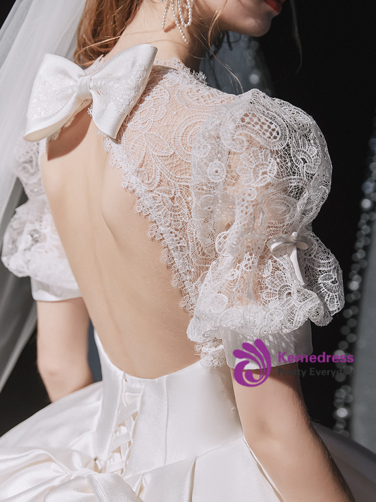 White wedding gown showing open back framed by floral lace puff sleeves and satin bow
