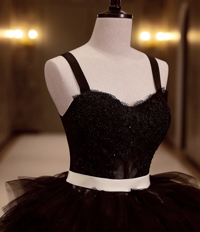 Closer view of the black gown's embellished bodice and ivory satin belt above the layered tulle skirt