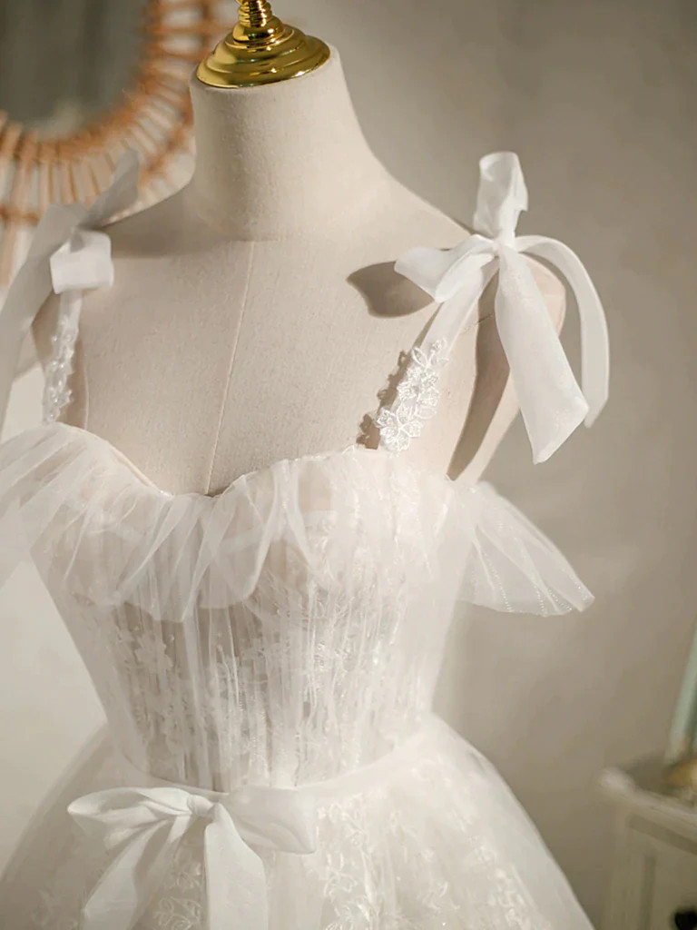 Close up of soft floral lace and tulle bow straps on a white homecoming dress