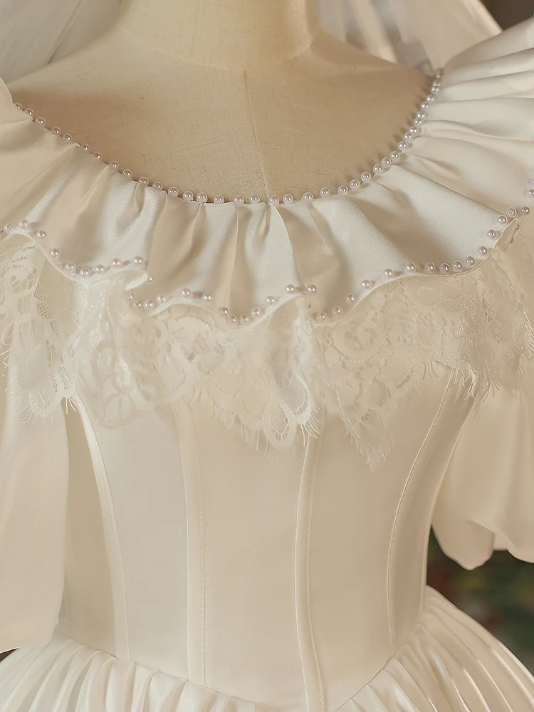 Close up of white satin wedding dress with floral lace and pearl embellishment