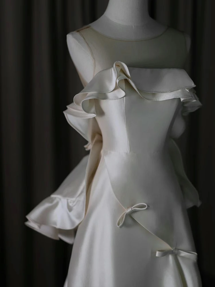 Ivory satin wedding dress with deep open back oversized bow cascading ruffles and chapel train