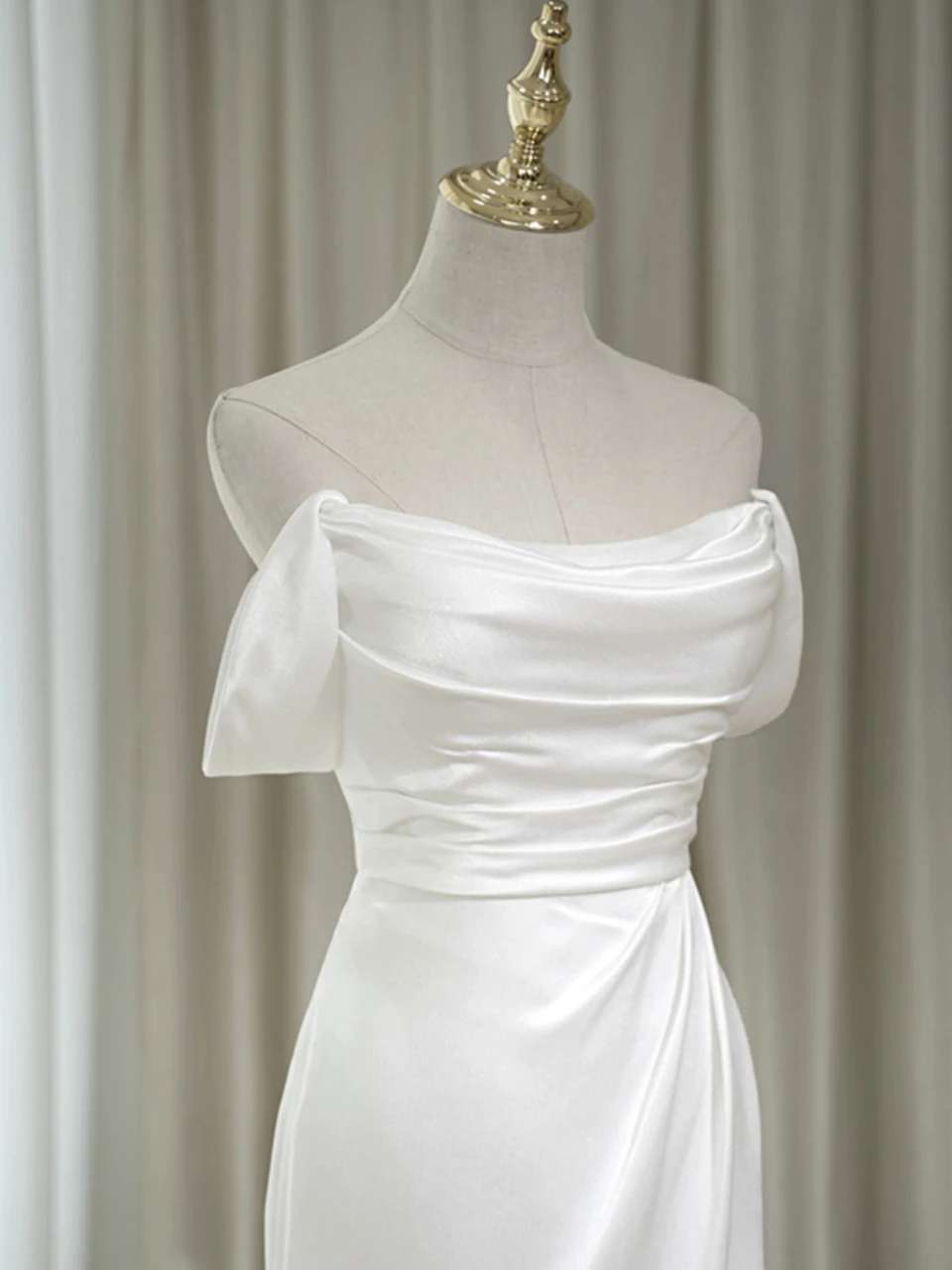 White satin off the shoulder wedding dress with draped neckline and pleated bodice detail