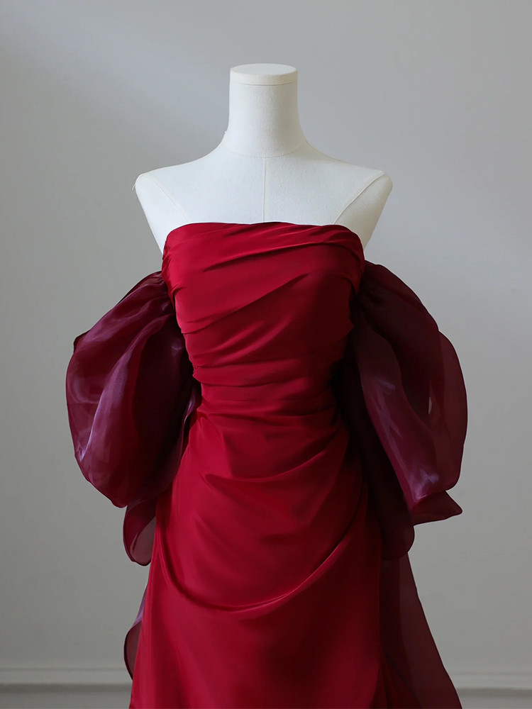 Close up of burgundy satin prom dress showing pleated draping and rich silky fabric texture