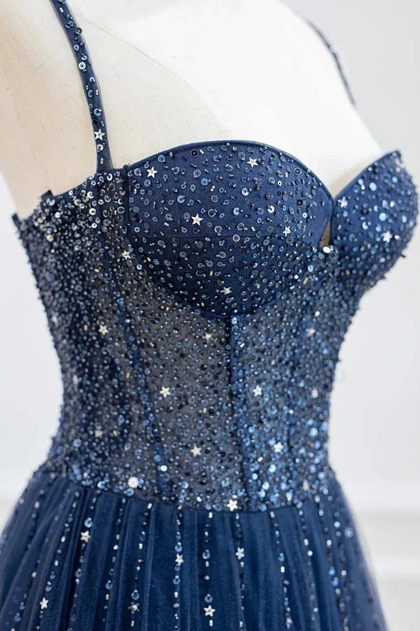 Close up detail of midnight blue tulle prom dress with beaded straps, star appliques and sequin embellishment