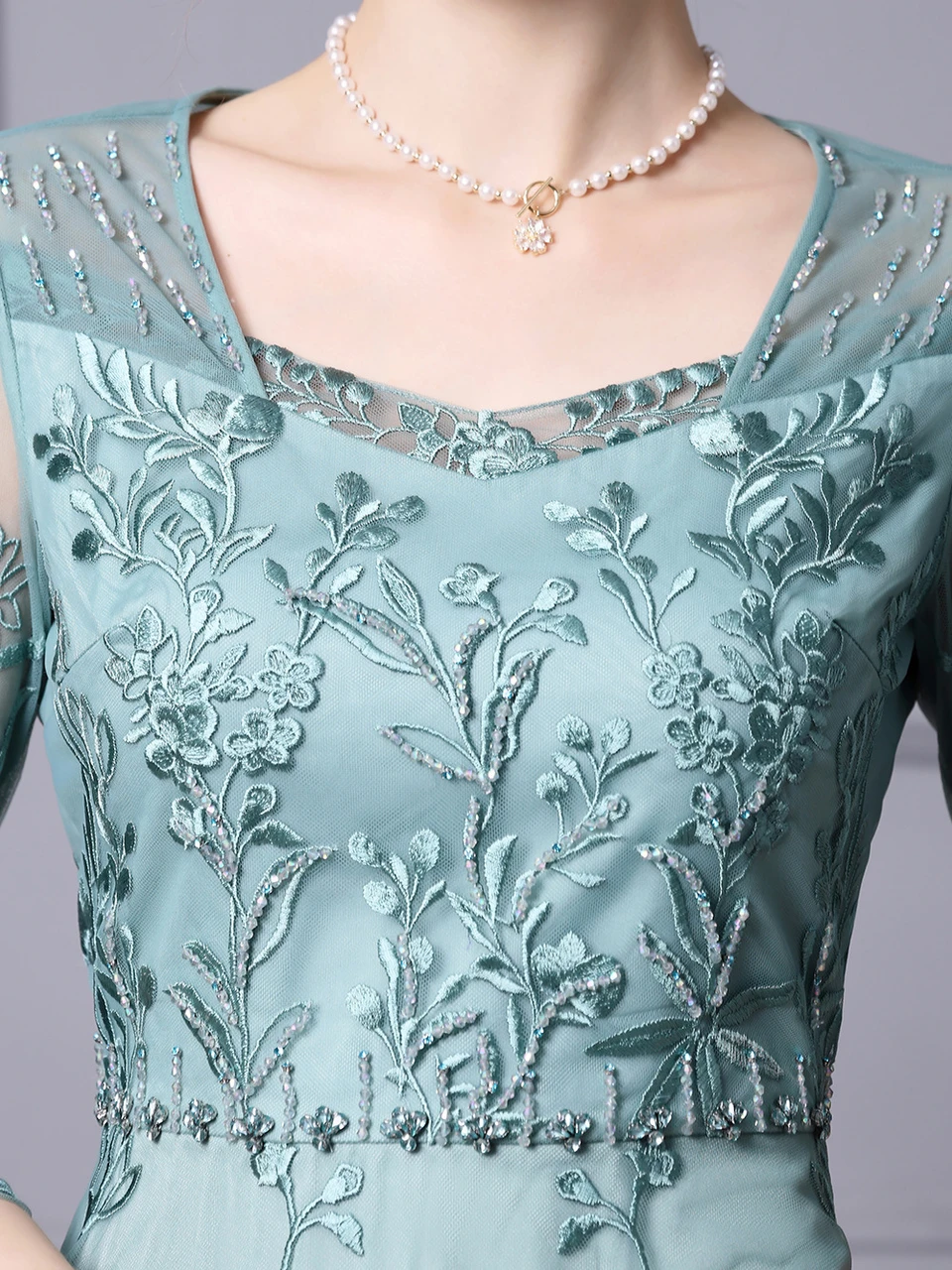 Close up of mint green tulle with dimensional floral leaf appliques and delicate beading