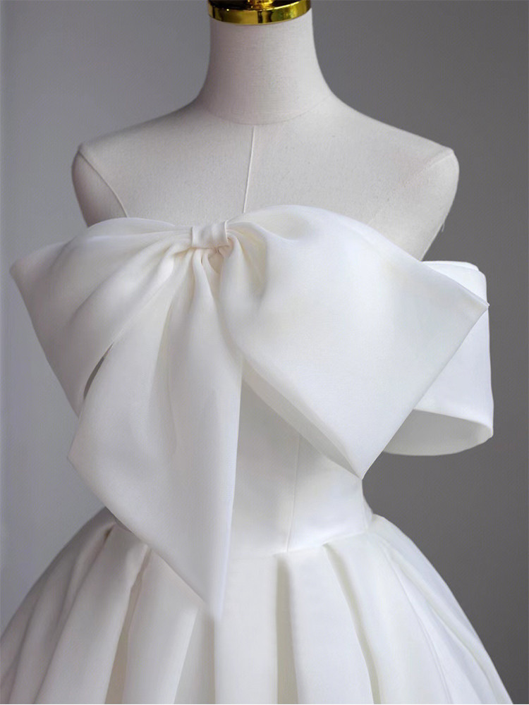 Ivory strapless satin ball gown wedding dress with oversized bow and full pleated skirt