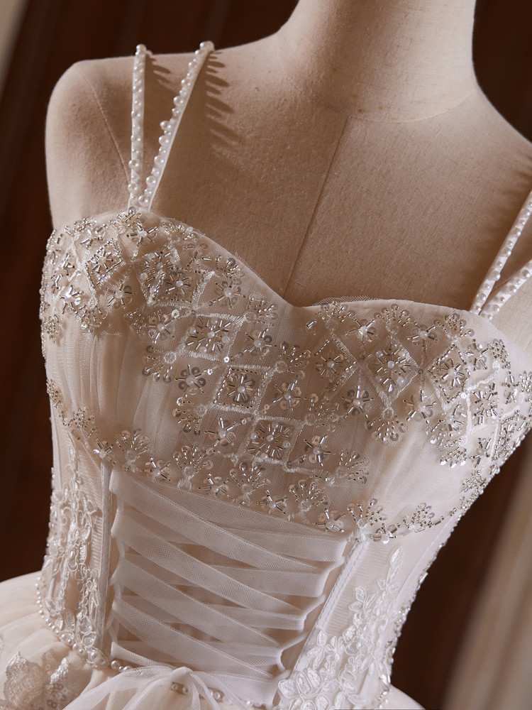 Close up of white tulle homecoming dress with mixed beadwork, lace details and delicate beaded straps