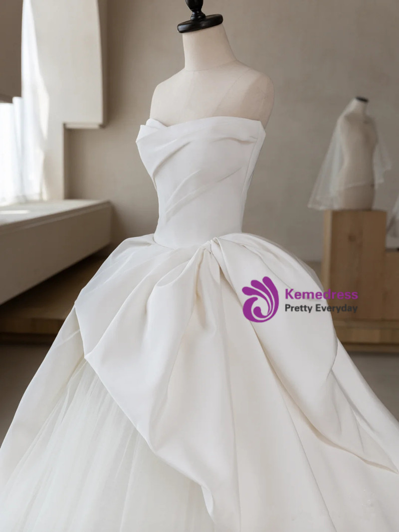 White satin tulle strapless sculptural ball gown wedding dress with oversized bow and cathedral train