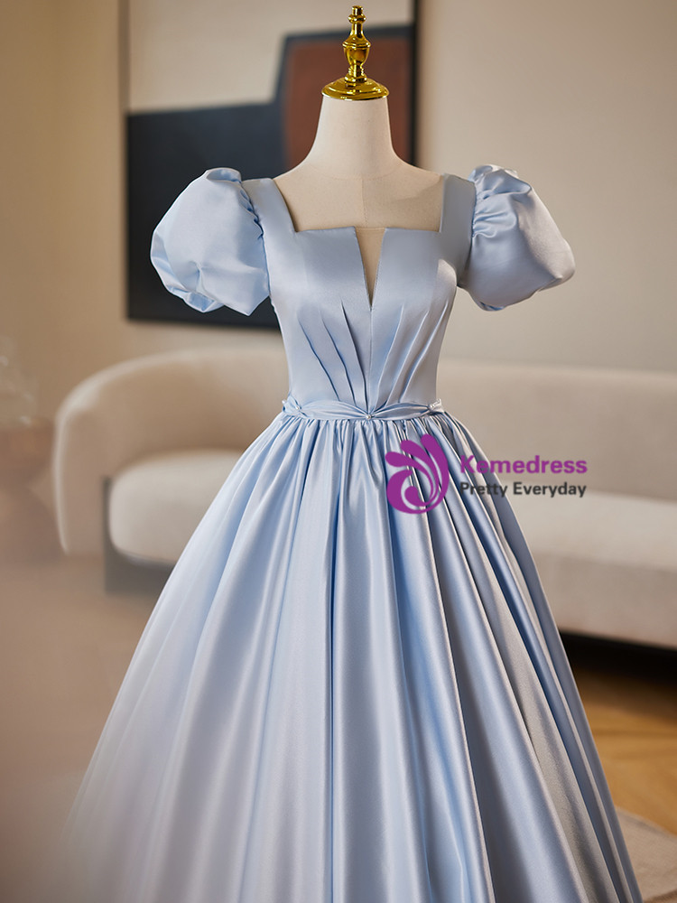 Detail view of the light blue satin gown showing its bodice pleats, rounded puff sleeves and softly reflective fabric