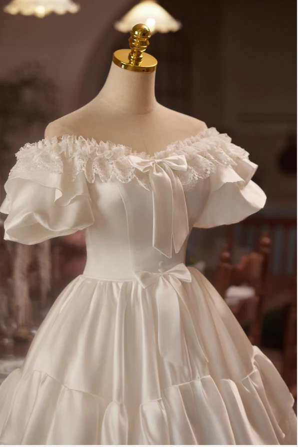 Close up of vintage lace, satin bows and tiered white satin homecoming dress