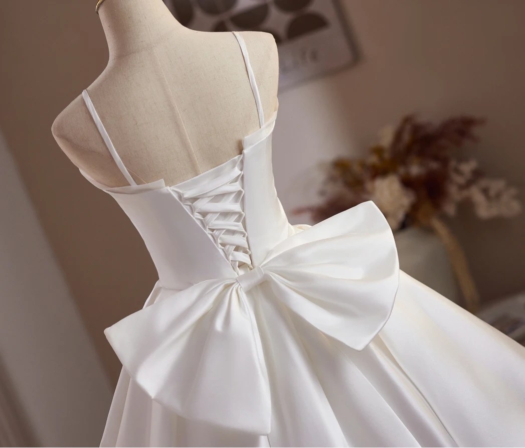 White satin short homecoming dress with spaghetti straps and oversized back bow