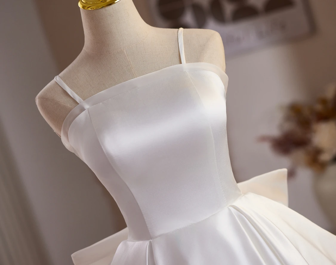 Close detail of white satin homecoming dress with structured bodice and bow sash