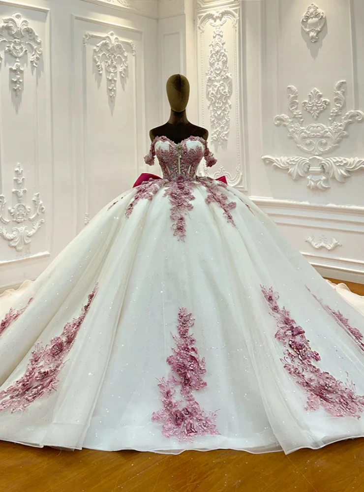Close detail of dusty pink 3D floral appliques on sparkling white tulle wedding dress