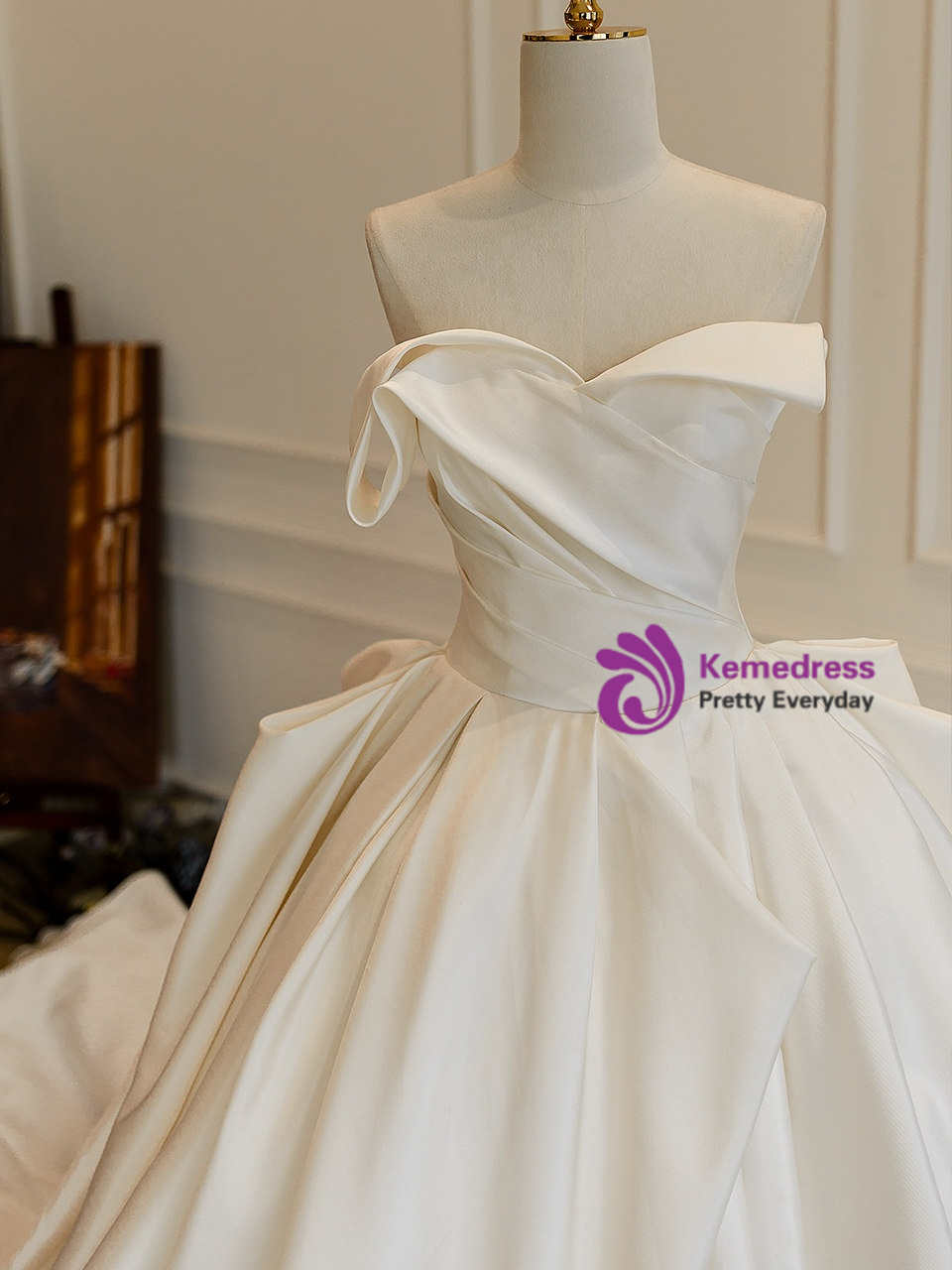 Ivory satin bridal gown with off shoulder neckline and draped pleated bodice