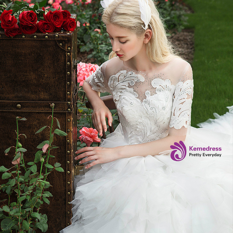 White ball gown wedding dress with feather inspired lace appliques, illusion short sleeves and layered ruffled tulle train