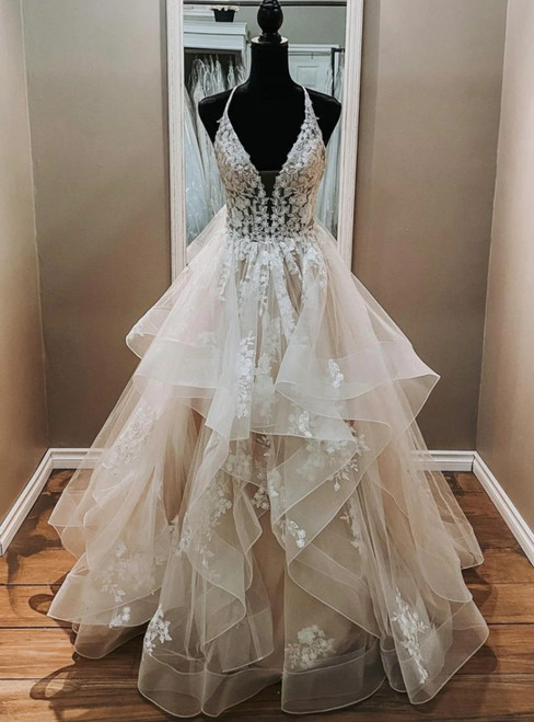 Champagne tulle appliqué V-neck wedding dress with a beaded bodice and flowing ball gown skirt.