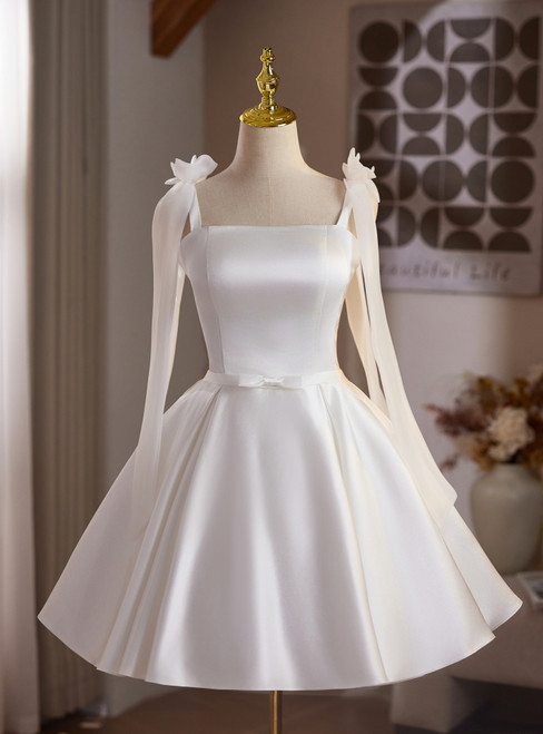 White satin A-line homecoming dress featuring detachable sheer sleeves with bow accents at the shoulders, a square neckline, and a flared knee-length skirt.