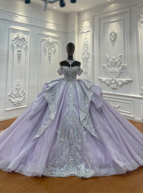 A lavender tulle ball gown, its off-shoulder bodice adorned with beaded floral appliqués that gleam softly like dewdrops on petals at twilight.