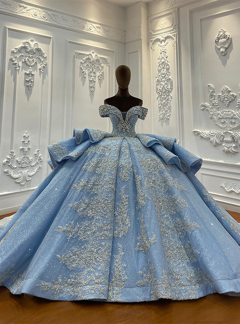 A crystal blue tulle ball gown that captures the light like ice, its off-shoulder bodice adorned with icy appliqués that shimmer with a cool, serene glow.