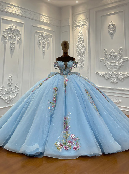 A serene blue off-shoulder wedding dress with a full tulle skirt, the bodice adorned with delicate appliques that catch the light.