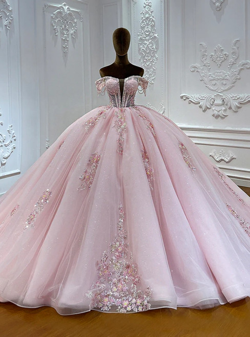 Pink tulle ball gown wedding dress with an off-the-shoulder neckline, delicate lace appliques, and a full flowing skirt.