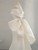 Back of an ivory satin mermaid wedding dress featuring a large statement bow, a stunning focal point for the aisle walk