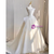 Side view of a white organza wedding dress, highlighting the voluminous A-line silhouette and the graceful train